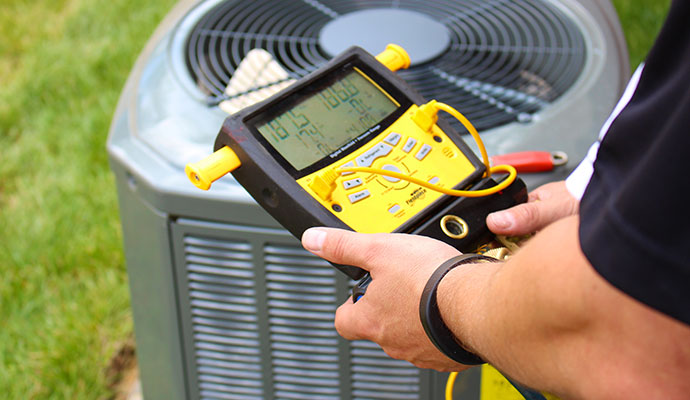 A technician diagnoses an outdoor residential air conditioning compressor unit