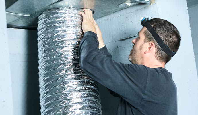 A professional installing duct pipe