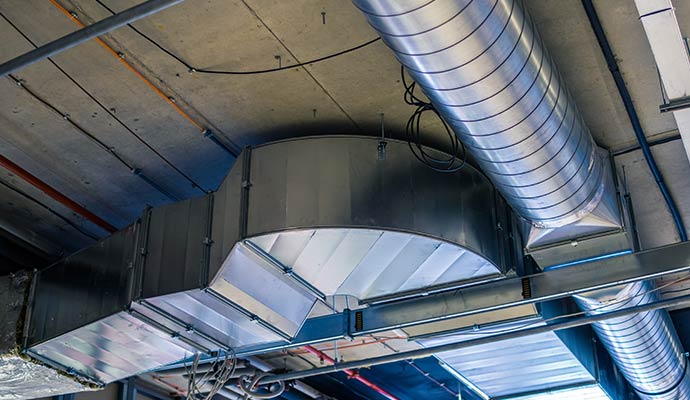Metal air duct pipes suspended below a raw concrete ceiling