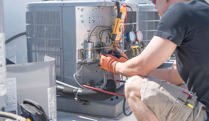 HVAC technician repairing AC unit electrical components