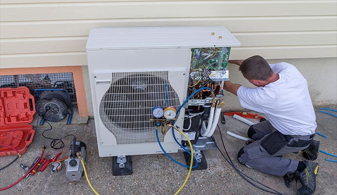 HVAC technician servicing outdoor heat pump with gauges