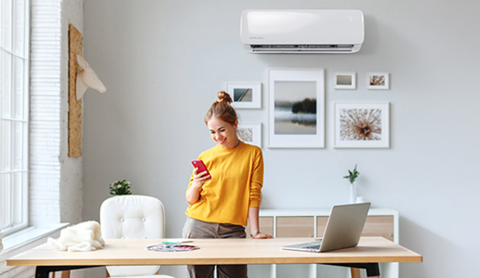 A woman standing in modern home office with mini split AC mounter on the wall