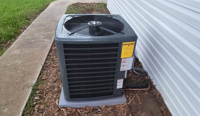 Outdoor AC condenser unit with refrigerant lines next to a house