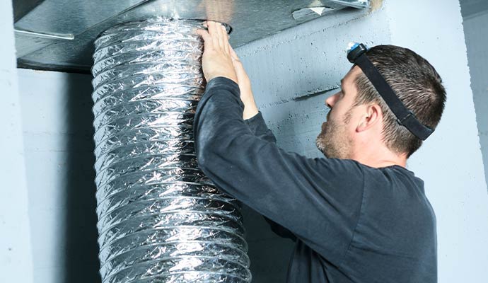 Technician installing flexible air duct in basement